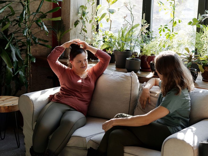 Person-centered disability support in Bryant, Arkansas: a support worker and a young woman with Down syndrome talk at home.